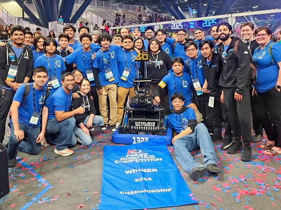 Madtown Robotics team gathered around their robot with the trophy and the FRC 2025 winners banner at their feet.